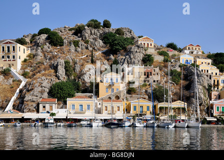 Yachten und Boote vor bunten traditionellen Häuser in Symi Hafen, Insel Symi, Griechenland Stockfoto