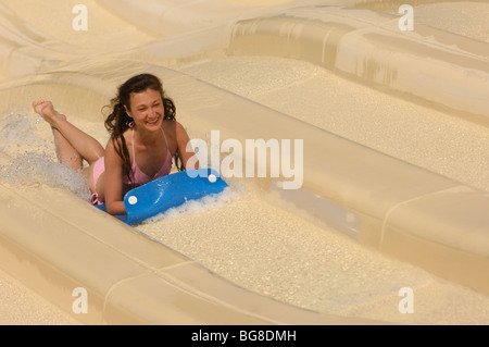 Junge lachende Frau auf einer Wasserrutsche in einen Wasserpark. Das Bild hat eine leichte Bewegungsunschärfe. Stockfoto