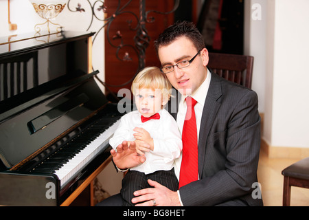 Vater umarmt Sohn in der Weihnachtsnacht neben dem Klavier spielen und lachen Stockfoto