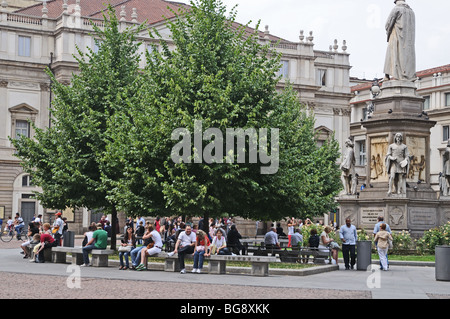 Menschen entspannen auf den Bänken im Piazza Dell Scala Mailand Mailand Italien Italia Opernhaus La Scala befindet sich hinter den Bäumen Stockfoto