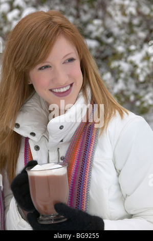 Mädchen trinken heißen Schokolade draußen im Schnee Stockfoto
