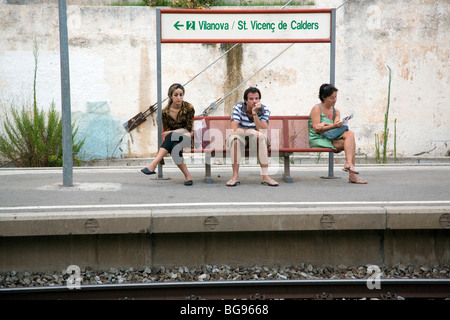 VOR MOBILTELEFONEN, 2007: Touristen warten und lesen auf dem Bahnsteig am Bahnhof Sitges in der Nähe von Barcelona Spanien in einer Zeit vor Mobiltelefonen Stockfoto