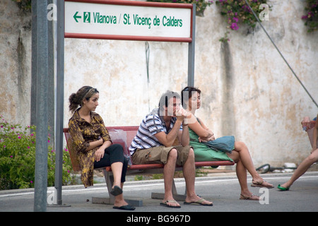 VOR MOBILTELEFONEN, 2007: Touristen warten auf einer Bank, denken auf dem Bahnsteig am Bahnhof Sitges in der Nähe von Barcelona, Spanien, in einer Zeit vor Mobiltelefonen Stockfoto