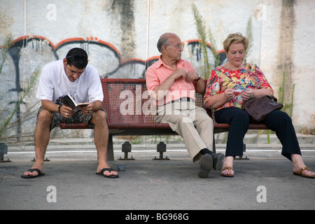 VOR MOBILTELEFONEN, 2007: Touristen warten und lesen auf dem Bahnsteig am Bahnhof Sitges in der Nähe von Barcelona Spanien in einer Zeit vor Mobiltelefonen Stockfoto