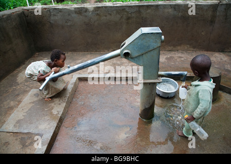 Kinder Pumpwasser aus dem Bohrloch, gebaut von einer internationalen NGO in ländlichen Malawi, Afrika Stockfoto