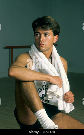 Junger Mann sitzt auf dem Boden in einem Fitnessstudio Stockfoto