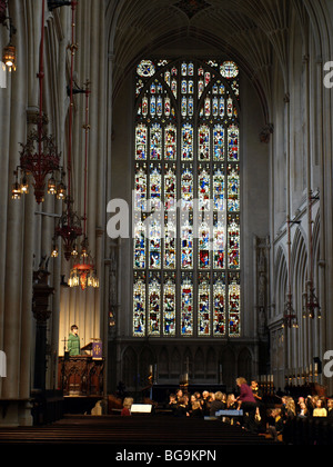 Schülerinnen und Schüler Proben Weihnachtslieder in Bath Abbey mit dem großen Ostfenster hinter in Bath, England, UK. Stockfoto