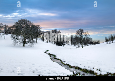 Sonnenuntergang, schneebedeckten Szene von sanften Hügeln, Bäumen und Stream entnommen Cotswold Way in der Nähe von Old Sodbury im Winter Stockfoto