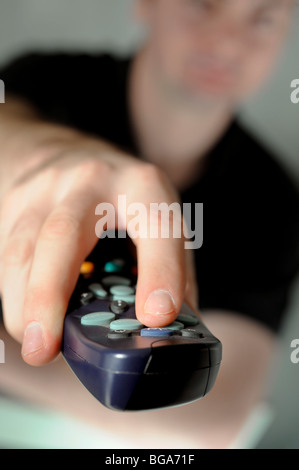 Ein junger Mann mit ein Sky-Digi-Box-Fernbedienung, um Kanal im Fernsehen zu ändern. Bild von Jim Holden. Stockfoto