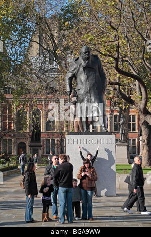 Besucher von London neben der Statue von Sir Winston Churchill, Ivor Roberts-Jones, in Parliament Square, London, UK. Stockfoto