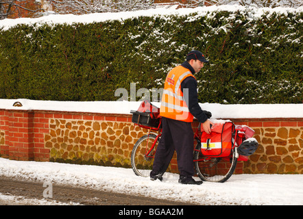 Ein Postbote kämpft sich durch den Schnee mit seinem Fahrrad die Weihnachtspost zu liefern. Stockfoto