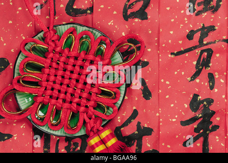 Roten Glücksknoten in einem Keramik-Platte, ist der Hintergrund Kalligraphie Segen Worte. Stockfoto