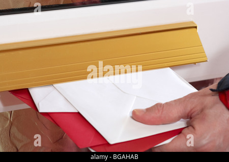 Postmans Hand schieben Briefe und Karten in den Briefkasten eines Hauses im Vereinigten Königreich Stockfoto