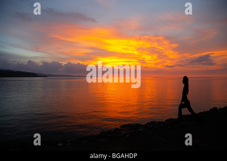 Silhouette einer Frau tun Yoga bei Sonnenuntergang an einem Strand in Nord-Sulawesi, Indonesien Stockfoto