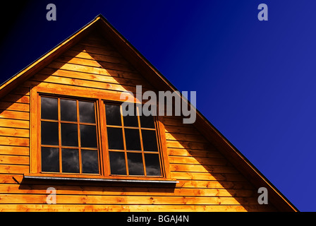 Das Dach von einem ländlichen Holzhaus auf einem blauen Himmelshintergrund. Stockfoto