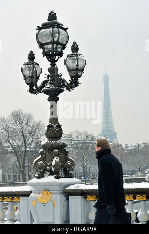 Paris, Frankreich, malerische Menschen im Schneesturm, Mann zu Fuß zur Arbeit, auf der Pont Alexandre III Brücke, mit Eiffelturm hinten, Winterstraße paris Schnee Stockfoto