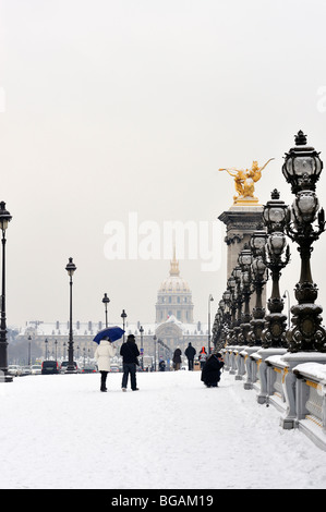 Paris, Frankreich, Winter kleine Gruppe von Menschen im Schneesturm, Paar Touristen, die auf der Brücke „Pont Alexandre III“ laufen, mit dem Invalidengebäude hinten Stockfoto