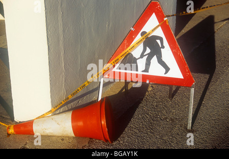 Rote und weiße Roadworker Zeichen und Verkehr Kegel auf seiner Seite mit gelben Klebeband besagt Nasslack neben Creme bemalten Wand Stockfoto