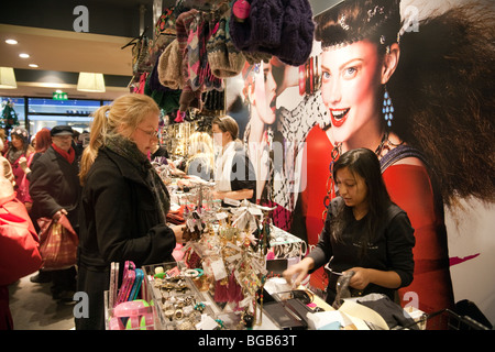 Shop Assistant Verkauf von Waren an Menschen Einkaufen in einem Monsoon Accessorize Store, Cambridge UK Stockfoto