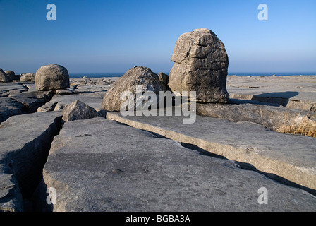 Irland, County Clare, Burren, Felsbrocken auf Kalkstein Pflaster Abschnitt in der Nähe von Black Head mit dem Atlantischen Ozean hinter. Stockfoto