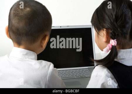 Jungen und Mädchen benützen einen laptop Stockfoto