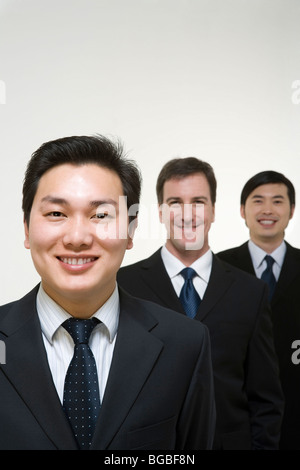 Drei Business-Profis in dunklen Anzügen auf hellem Hintergrund Stockfoto