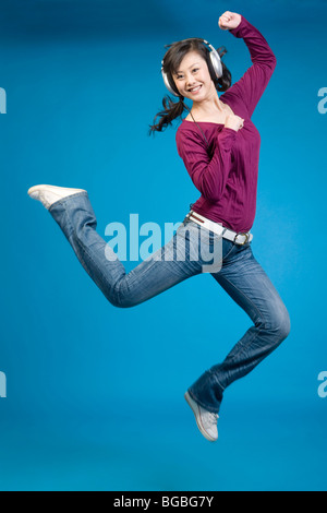 Frau, zuhören, Kopfhörer und springen vor Freude Stockfoto