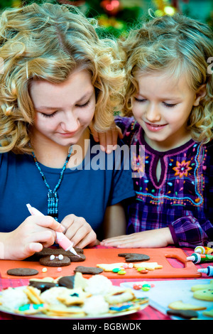 Weihnachten backen, 13 und 7 Jahre alten Mädchen schmücken Weihnachtsplätzchen Stockfoto