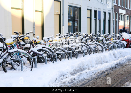 Eine Reihe von Schnee bedeckt Fahrräder in der niederländischen Stadt Groningen Stockfoto