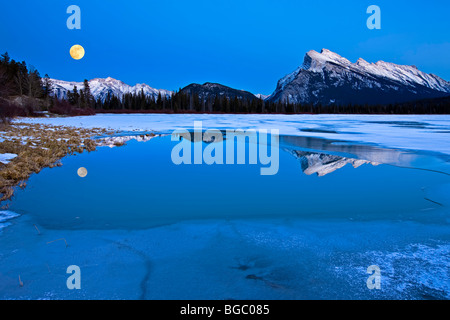 Schneebedeckten Mount Rundle (2949 m/9675 Fuß) und Tunnel Mountain (1692 m/5551 Fuß) mit Reflexionen auf einem teilweise her Stockfoto