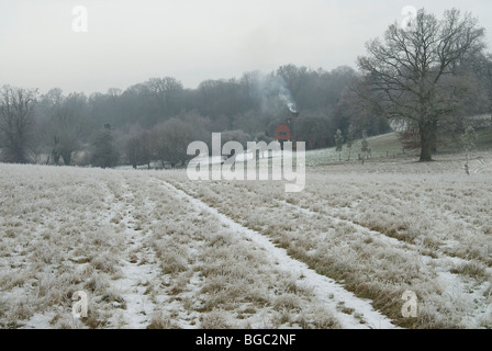 Anwendungsbereich im Schnee mit einem kleinen Häuschen mit Rauch aus dem Schornstein mitten im winter Stockfoto