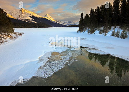 Teilweise gefrorenen Maligne River als es entzieht Maligne-See im Winter mit Blick auf die schneebedeckten Berge von Lea Stockfoto