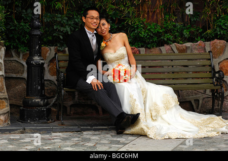 Chinesische Hochzeitspaar in ein langes Kleid und einen dunklen Anzug sitzt auf einer Bank, Hong Kong, China, Asien Stockfoto