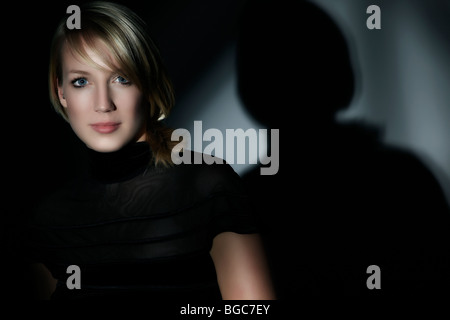 Porträt einer jungen Frau, umgeben von Schatten, direkten Blick Stockfoto