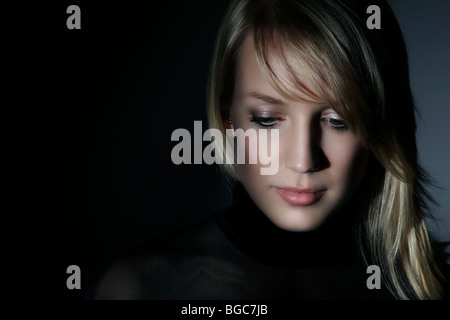 Junge Frau, umgeben von Schatten, Blick nach unten Stockfoto