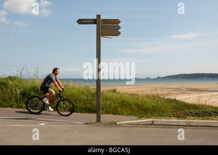 Radsportler an Swansea Strandpromenade, mit dem Strand und The Mumbles im Hintergrund, West Glamorgan, South Wales U.K Stockfoto