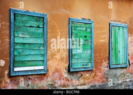 Drei Fenster eines heruntergekommenen Altbaus vernagelt. Stockfoto