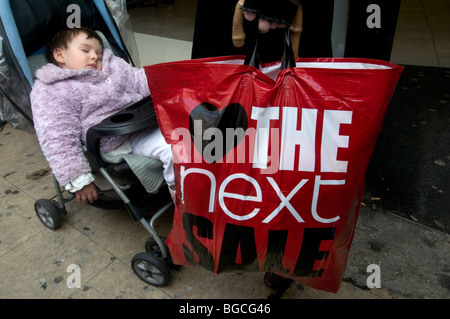 Oxford Street: Boxing Day 2009 Sales.Baby schlafend im Kinderwagen neben Vater mit nächsten Verkauf Tasche. Stockfoto