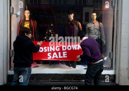 Oxford Street Boxing Day 2009 Sales.Two Männer setzen eine Schließung Verkaufsschild im Schaufenster Stockfoto