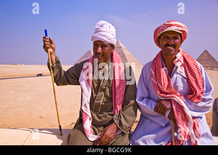 Zwei männliche ägyptische Kameltreiber, die Kamelreiten bei den Pyramiden von Gizeh nahe Kairo Ägypten geben Stockfoto