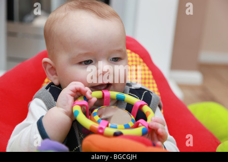 3 - 4 Monate alten Jungen spielen mit Spielzeug in Wiege Stuhl Stockfoto