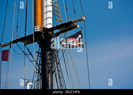 Piratenflagge am Mast eines Schiffes angehoben Stockfoto