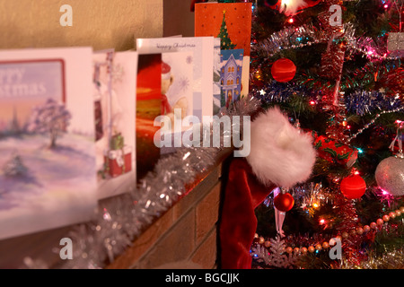 Weihnachts-Strumpf hängen unter der Zeile der Weihnachtskarten auf einem Kaminsims in ein Weihnachtsfest eingerichtete Wohnzimmer im Vereinigten Königreich Stockfoto