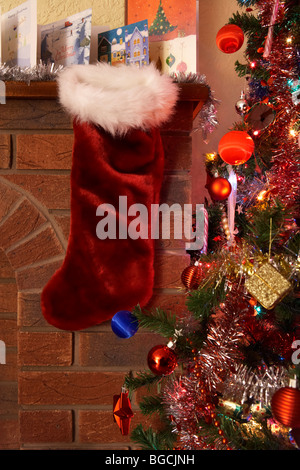 leere Weihnachts-Strumpf hängen unter der Zeile der Weihnachtskarten auf einem Kaminsims in ein Weihnachtsfest eingerichtete Wohnzimmer im Vereinigten Königreich Stockfoto