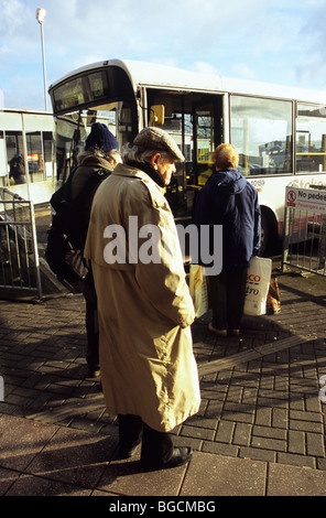 Alten älterer Mann allein In Regenmantel und warten auf einen Bus am Busbahnhof Hanley Bord-Cap Stockfoto