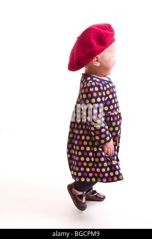 1 Jahr alt kleine Mädchen tragen große rote Mütze Spaziergänge entfernt isoliert auf weiss Stockfoto