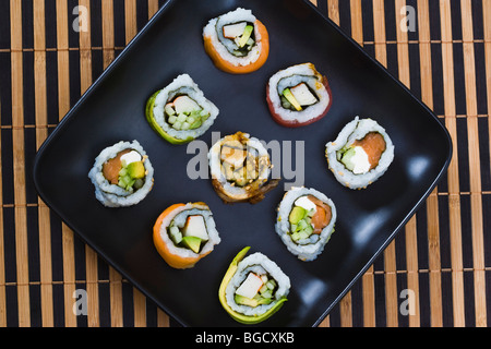 Verschiedene Sushi-Rollen auf schwarzem Teller, Nahaufnahme Stockfoto