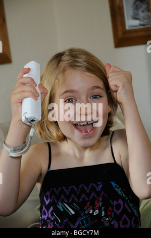 Porträt eines jungen Mädchens mit einem Wii game-Controller und sah aus wie sie nur ein Spiel gewonnen hat Stockfoto