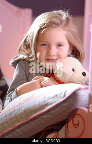 Kleines Mädchen mit ihrem Stofftier Lyubg zwischen Kissen auf ihrem Bett Stockfoto