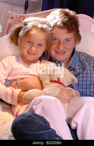 Bruder und Schwester im Bett spielen, ins Bett gehen, ins Bett nehmen, stopfte in Stockfoto